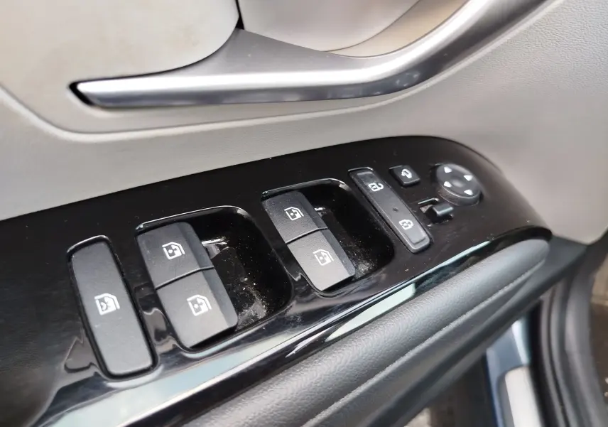 Gros plan sur les commandes de lève-vitres et rétroviseurs côté conducteur du Hyundai Tucson 2021 en Teal Blue Métal.