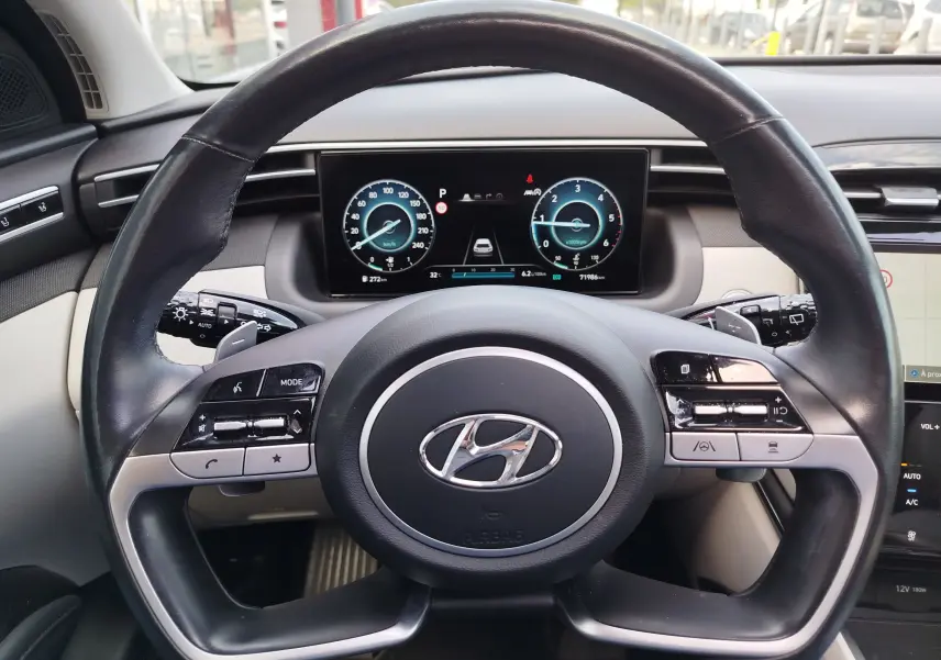 Vue rapprochée du volant cuir noir et du tableau de bord numérique du Hyundai Tucson 2021, intérieur beige et noir.