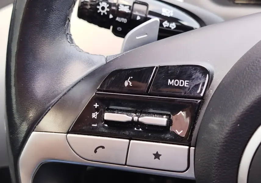 Gros plan sur les commandes gauche du volant noir du Hyundai Tucson 2021, boutons mode, volume et appel visibles.