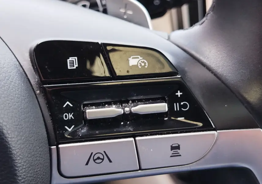 Gros plan sur les commandes au volant du Hyundai Tucson 2021, boutons noirs et argentés avec fonctions d'assistance à la conduite.