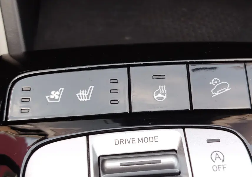Gros plan sur les commandes de confort et modes de conduite du Hyundai Tucson 2021, finition Executive, avec boutons noirs et icônes blanches.