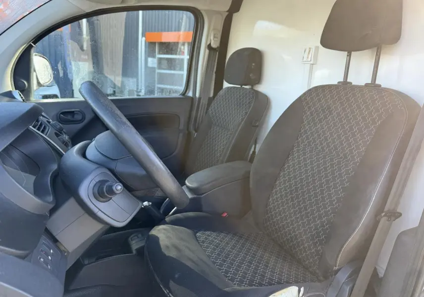 Intérieur du Renault Kangoo Express 2016, vue côté conducteur, sièges tissu noir à motifs gris et tableau de bord noir.