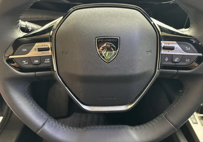 Gros plan sur le volant cuir noir de la Peugeot 308 PureTech 130 S&S Allure 2024 avec commandes multifonctions intégrées.