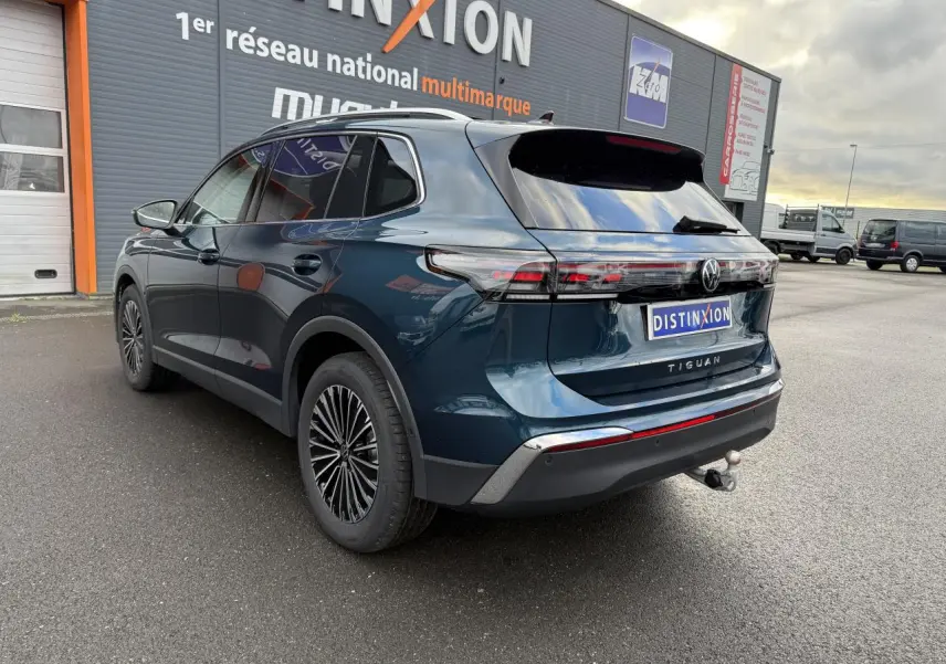 Vue 3/4 arrière droite du Volkswagen Tiguan 2024 bleu nuit métallisé avec crochet d'attelage et jantes alliage 18 pouces.