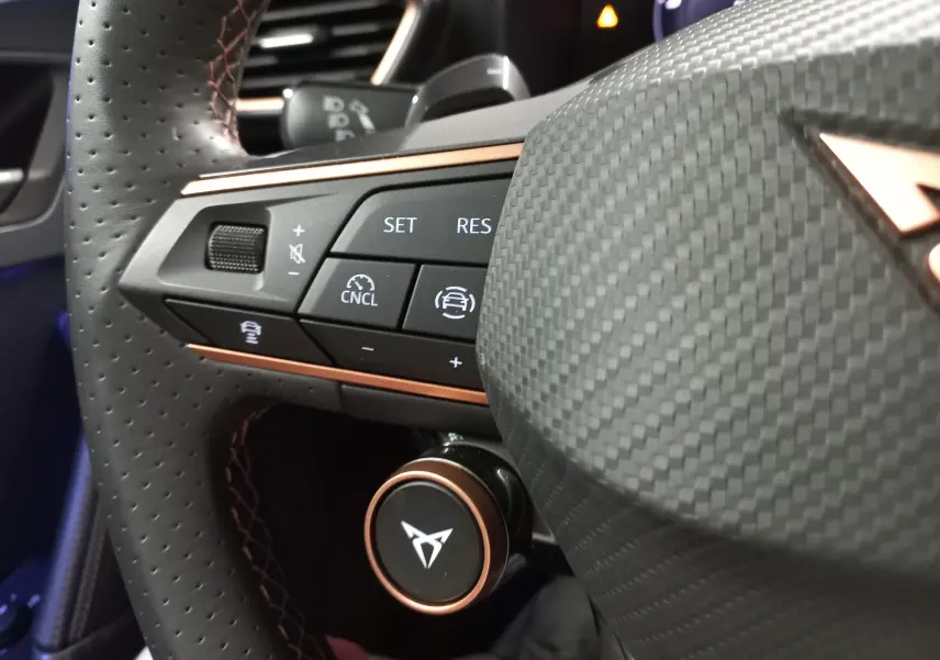 Gros plan sur le volant en cuir perforé avec commandes intégrées et logo CUPRA, intérieur du Formentor 1.5 EHybrid 2025.