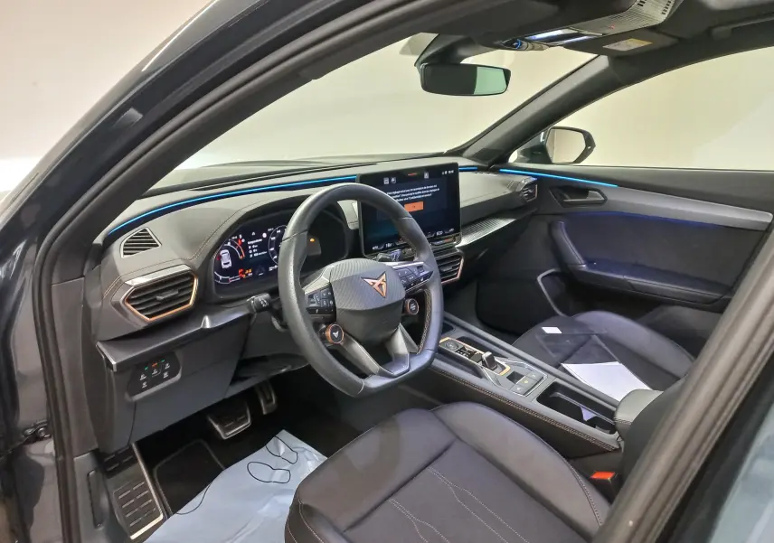 Vue intérieure côté conducteur de la CUPRA Formentor gris magnétique 2025, avec tableau de bord digital et éclairage d'ambiance bleu.