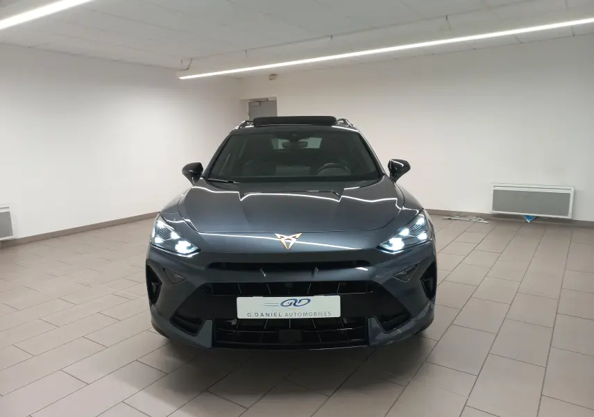 Vue avant d'une CUPRA Formentor gris magnétique avec phares allumés et toit ouvrant panoramique visible en intérieur.