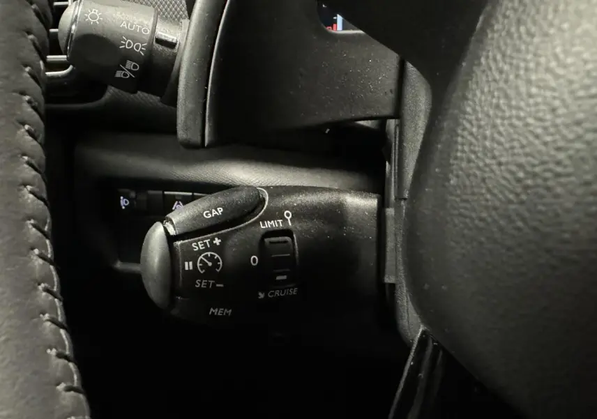 Gros plan sur la commande de régulateur de vitesse noire à gauche du volant d'un Citroën C5 Aircross 2022.