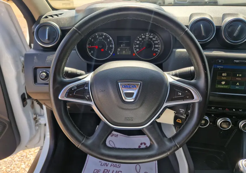 Vue intérieure centrée sur le volant noir du Dacia Duster 2021, avec tableau de bord et écran tactile visibles.