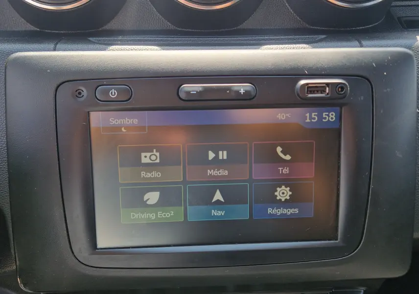 Écran tactile central du Dacia Duster 2021 blanc, affichant le menu multimédia avec options radio, navigation et téléphone.