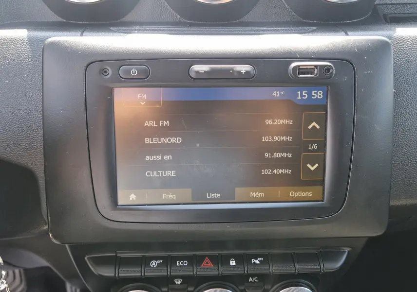 Écran tactile central du tableau de bord du Dacia Duster blanc 2021 affichant les stations radio FM.