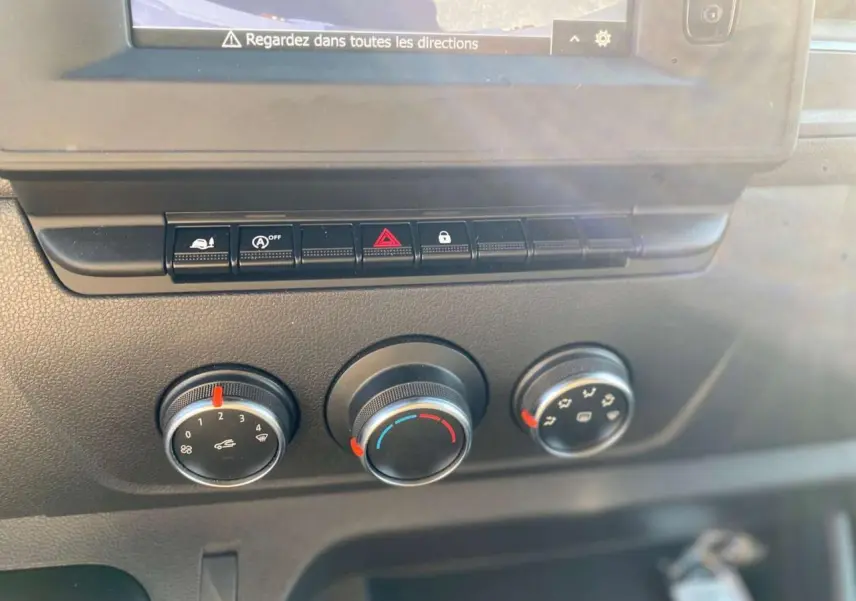 Gros plan sur les commandes de climatisation et les boutons de fonction du tableau de bord de l'Opel Movano Fourgon blanc.
