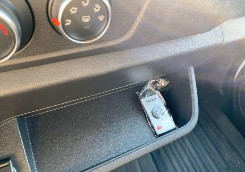 Gros plan sur la console centrale noire de l'Opel Movano Fourgon 2021 avec une télécommande emballée visible.