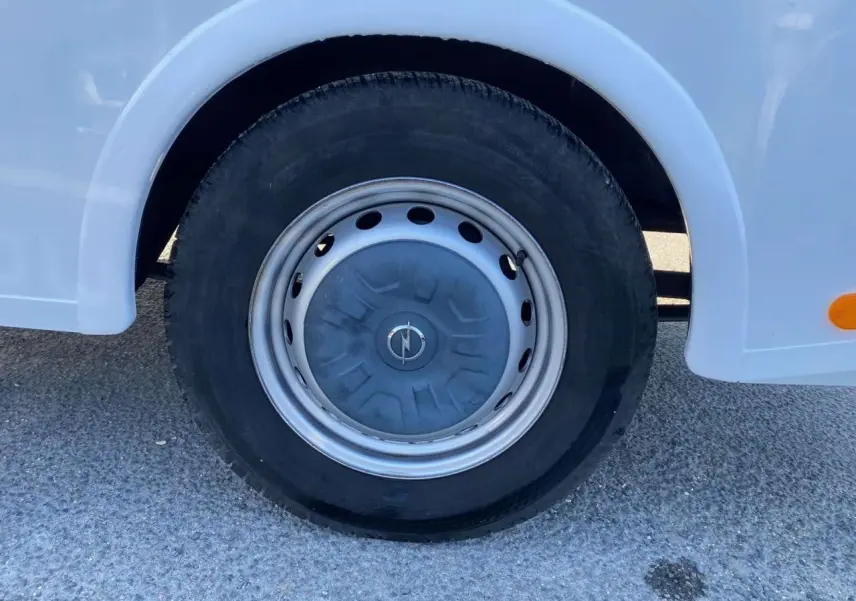 Gros plan sur la roue avant gauche blanche d'un Opel Movano Fourgon 2.3 CDTI avec jante acier et logo Opel central.