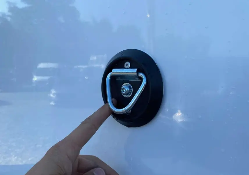 Gros plan sur une main touchant un anneau d'arrimage fixé sur la carrosserie blanche d'un Opel Movano Fourgon.