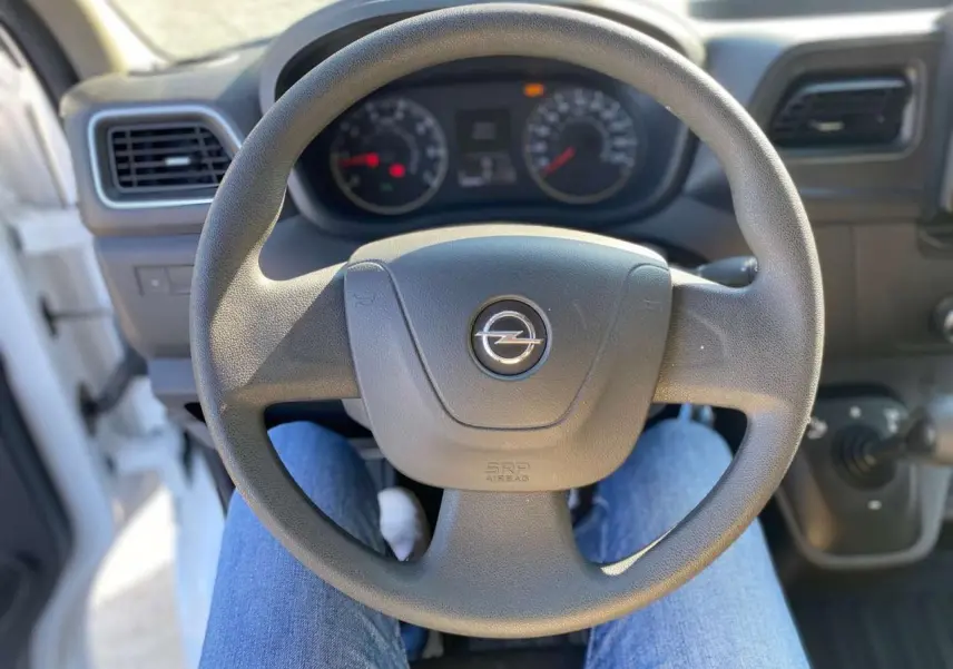 Vue rapprochée du volant noir de l'Opel Movano Fourgon blanc, avec tableau de bord et commandes visibles en arrière-plan.