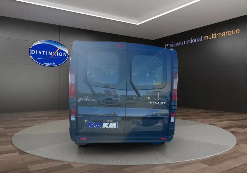 Vue arrière d'un Renault Trafic Combi gris comète avec portes battantes et logo Zero KM visible.