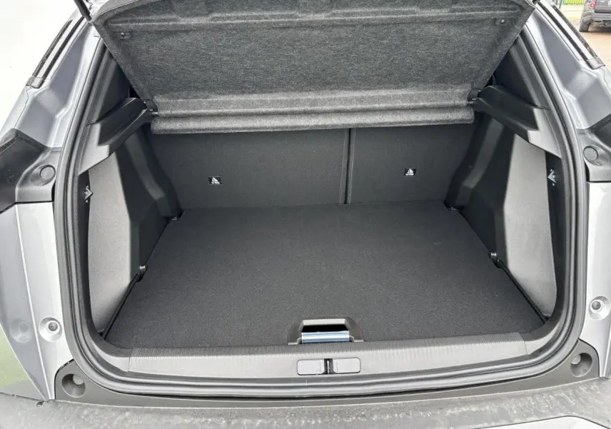 Coffre ouvert vu de l'arrière du Peugeot 2008 gris Artense avec intérieur noir et cache-bagages relevé.