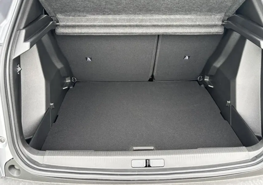 Coffre ouvert vu de l'arrière du Peugeot 2008 gris Artense avec intérieur noir et banquette rabattable.