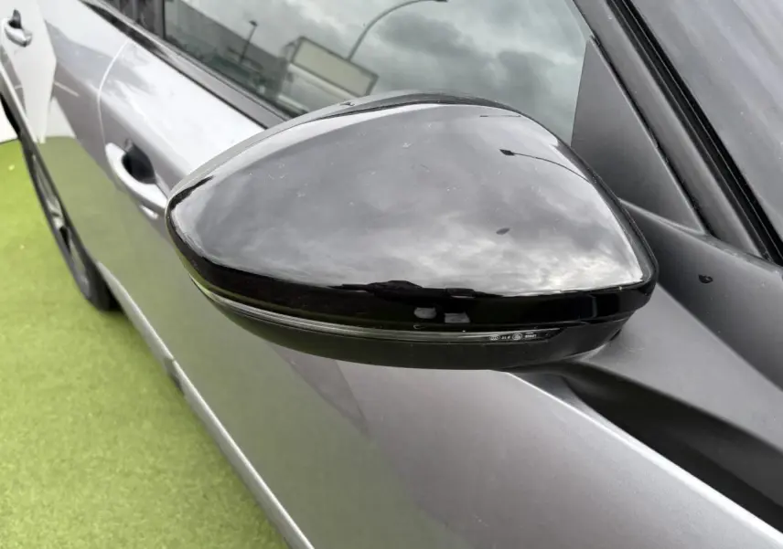 Rétroviseur côté gauche noir brillant sur Peugeot 2008 gris Artense avec toit noir, vue rapprochée en extérieur.