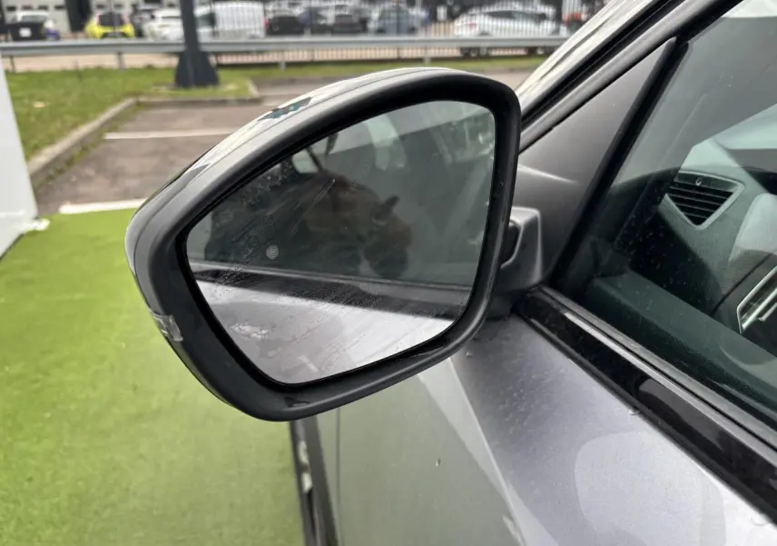 Rétroviseur côté gauche du Peugeot 2008 gris Artense avec toit noir, vue rapprochée sur la portière avant.