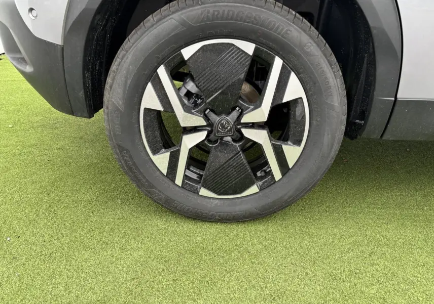 Gros plan sur la roue avant droite du Peugeot 2008 gris Artense avec jante alliage bi-ton noir et argent.