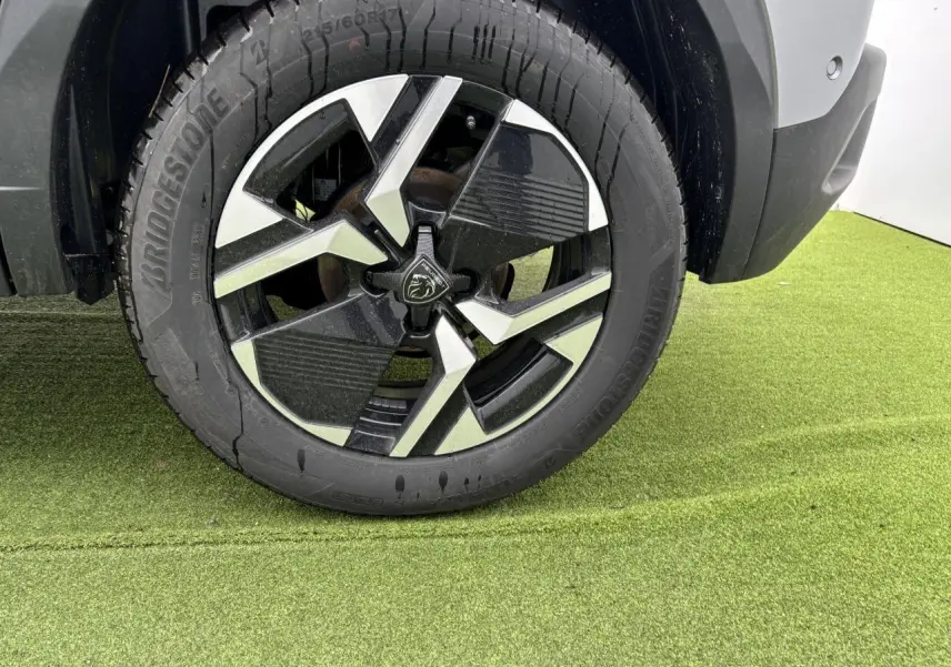 Gros plan sur la jante alliage 17'' bi-ton noir et argent du côté arrière droit d'un Peugeot 2008 gris Artense toit noir.