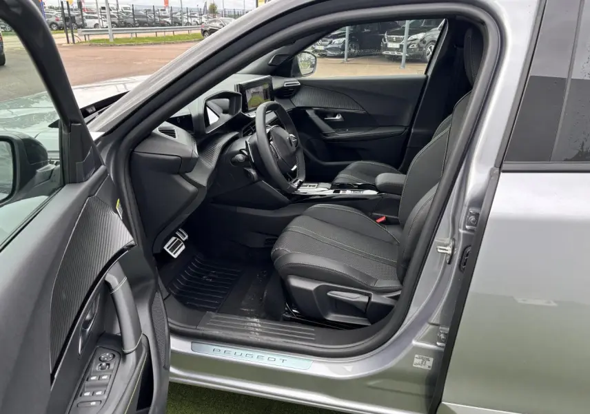 Intérieur côté conducteur du Peugeot 2008 gris Artense, montrant sièges tissu et volant compact cuir avec commandes.