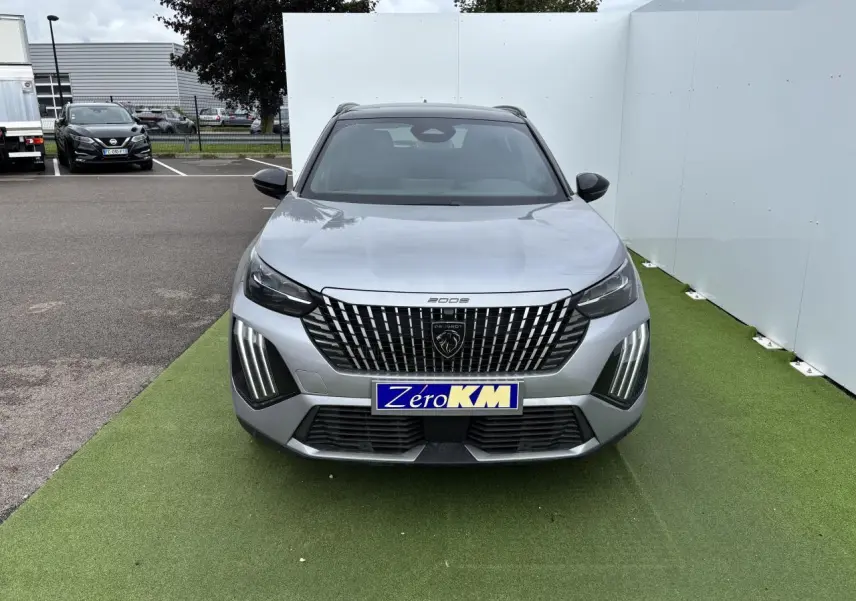 Peugeot 2008 gris Artense vue de face avec calandre verticale noire et feux LED 3 griffes allumés.