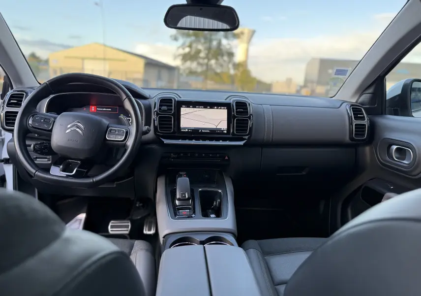 Vue intérieure avant du Citroën C5 Aircross blanc nacré, tableau de bord moderne avec écran tactile et volant multifonction.