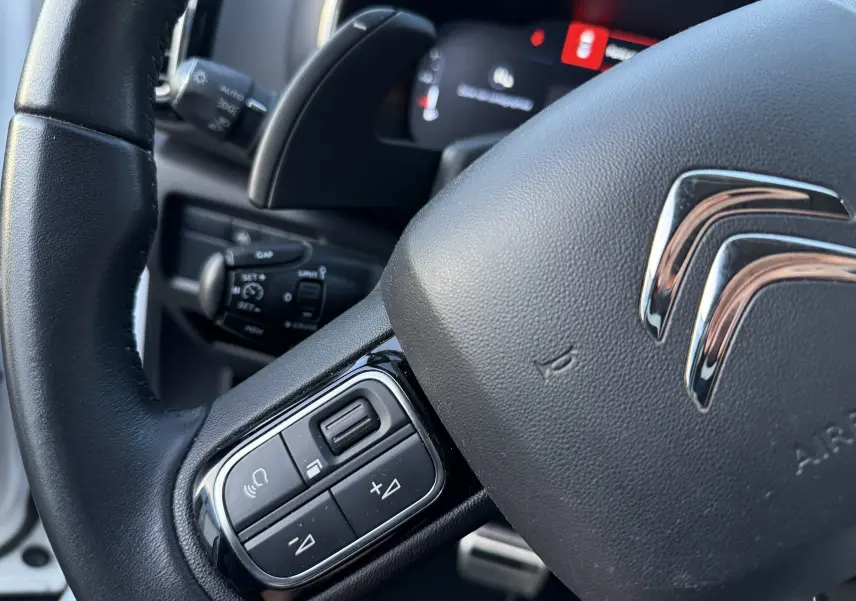 Gros plan sur le volant noir du Citroën C5 Aircross 2021 avec commandes intégrées et logo chromé visible.