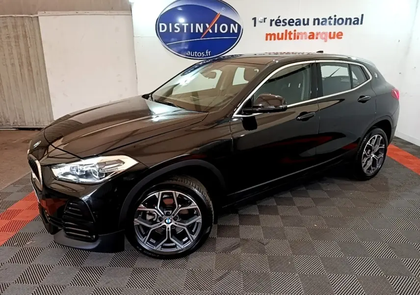 BMW X2 sDrive18i Lounge noire vue 3/4 avant droit dans un showroom avec jantes alliage distinctives.