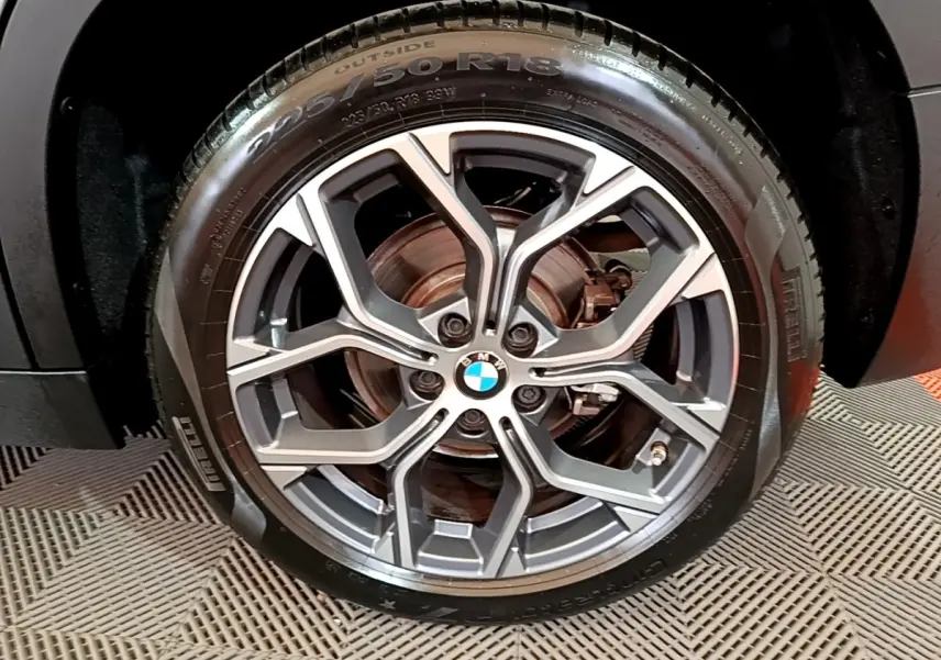 Gros plan sur la roue avant droite d’un BMW X2 noir 2023, jante alliage à design géométrique et pneu Pirelli.