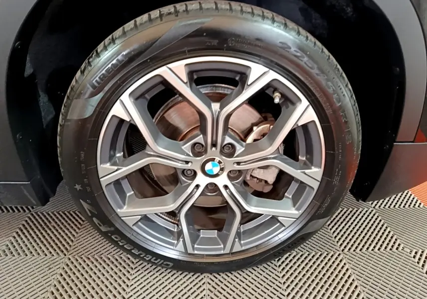 Gros plan sur la roue avant droite noire d’un BMW X2 sDrive18i Lounge 2023 avec jante alliage à design géométrique.