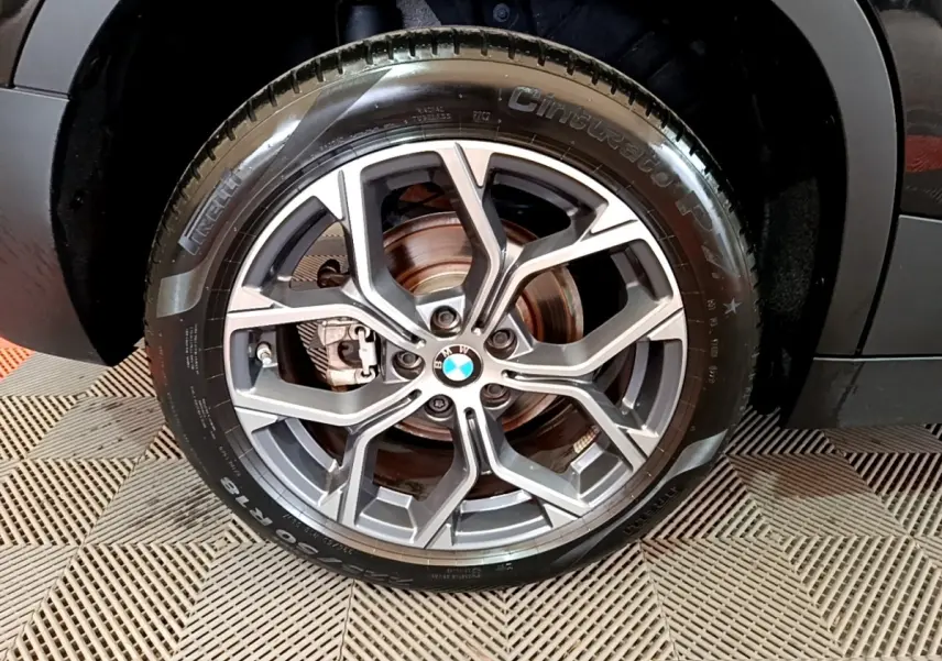 Gros plan sur la roue avant droite du BMW X2 sDrive18i Lounge noir, mettant en valeur la jante alliage et le pneu Pirelli.
