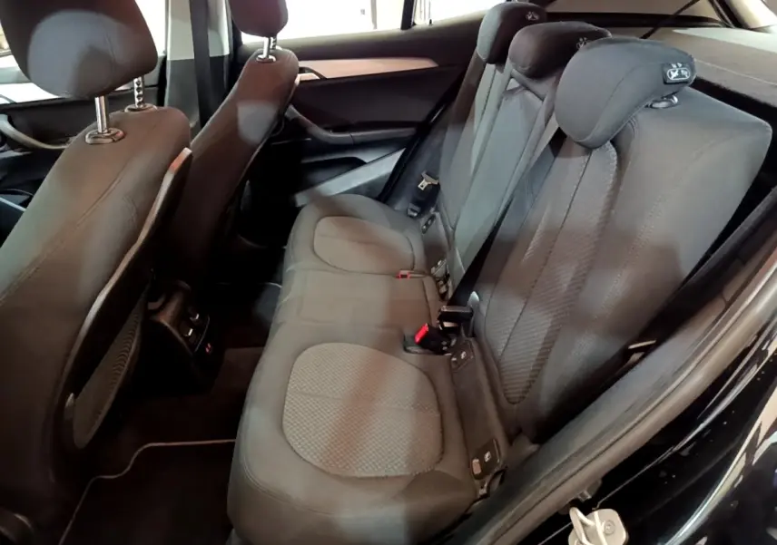 Vue intérieure arrière côté droit du BMW X2 sDrive18i Lounge 2023 noir, montrant la banquette et les appuie-têtes enfant.