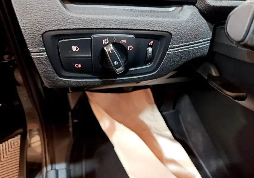 Détail du tableau de bord noir de la BMW X2 sDrive18i 2023 montrant la commande des phares et antibrouillards.