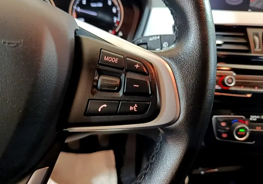 Gros plan sur le volant multifonctions en cuir noir et la console centrale du BMW X2 sDrive18i Lounge 2023.