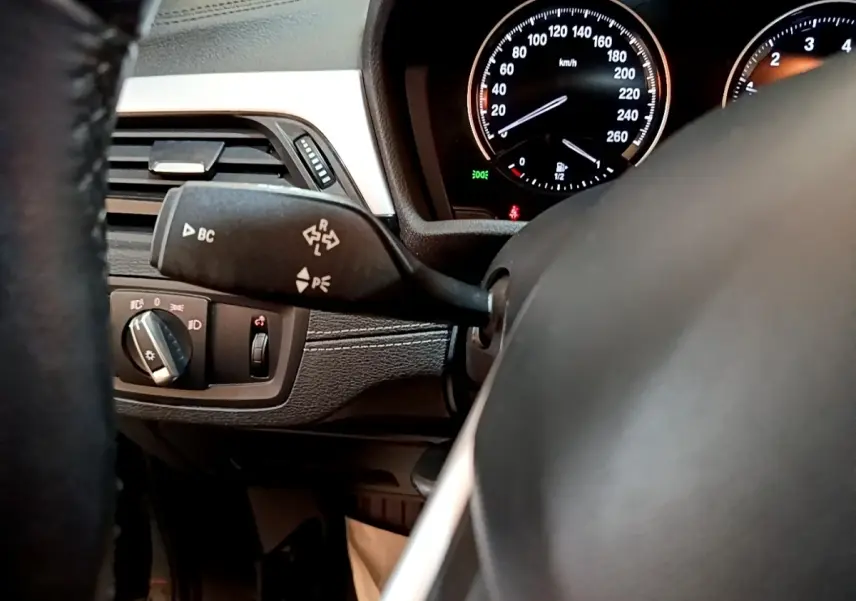 Détail intérieur côté gauche du tableau de bord noir de la BMW X2 sDrive18i Lounge 2023 avec commandes et compteur.