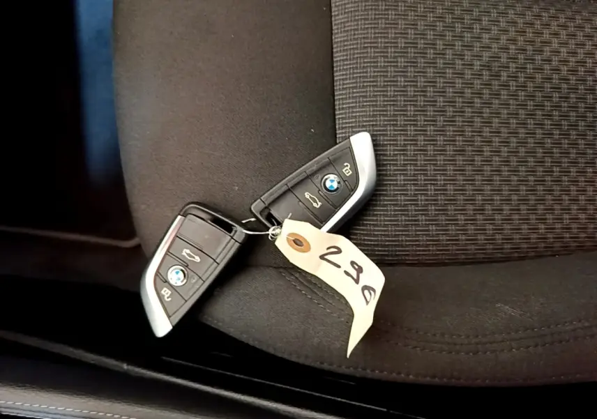 Gros plan sur deux clés BMW posées sur un siège tissu noir avec étiquette numérotée 298.