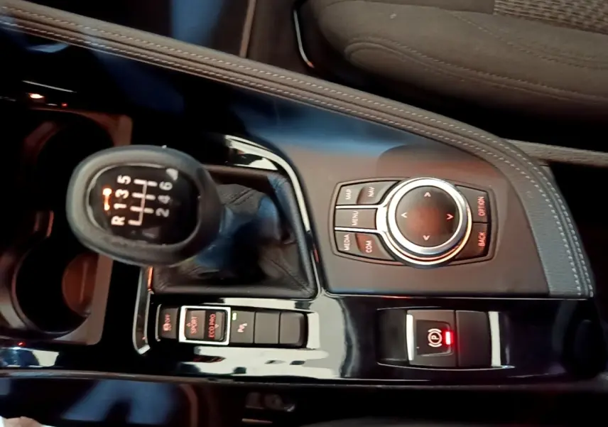 Vue rapprochée de la console centrale noire du BMW X2 sDrive18i 2023 avec levier de vitesses manuel et molette de contrôle.