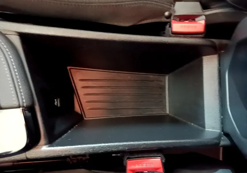 Gros plan de la console centrale noire du BMW X2 sDrive18i Lounge 2023 avec boutons de ceinture rouges visibles.