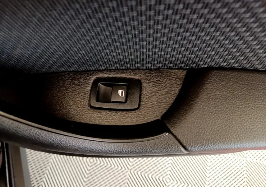 Bouton de commande de lève-vitre arrière droit sur la porte intérieure noire d’un BMW X2 sDrive18i Lounge 2023.