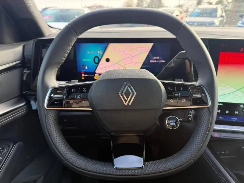 Vue frontale du volant noir perforé du Renault Austral 2025 avec logo central et tableau de bord numérique affichant une carte.