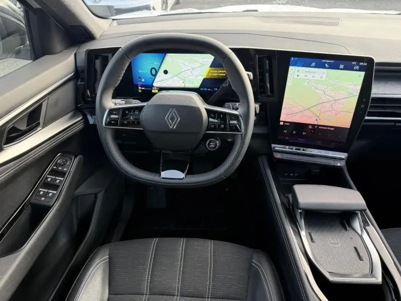 Vue intérieure du poste de conduite du Renault Austral 2025, avec volant multifonction et double écran numérique affichant la navigation.