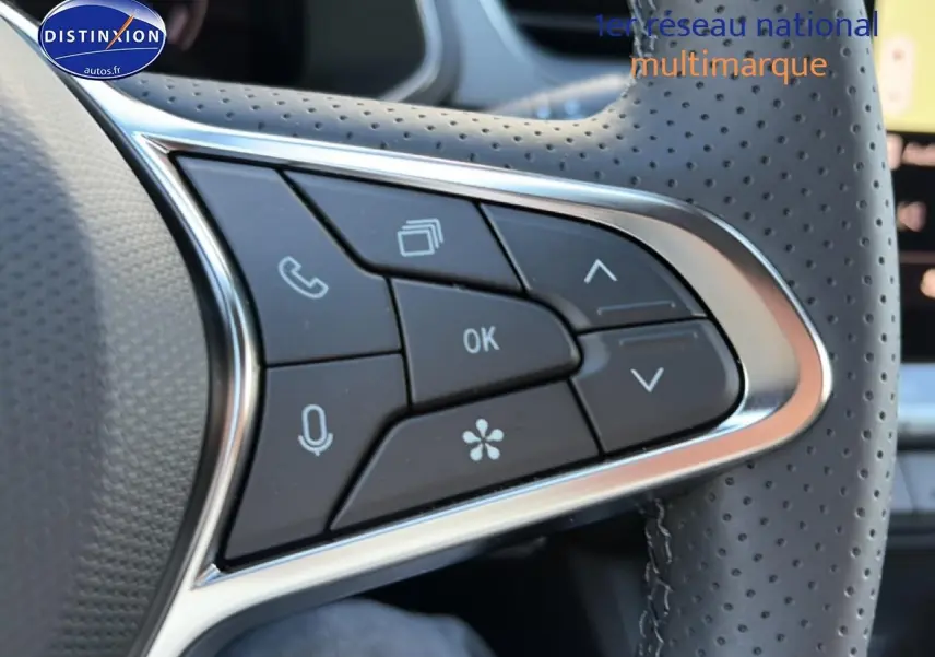 Gros plan sur les commandes multifonctions au volant en cuir perforé du Renault Captur 2026 bleu iron toit noir.