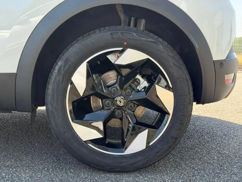 Gros plan sur la roue avant droite du Renault Captur blanc nacré, avec jante alu noire et argentée au design géométrique.