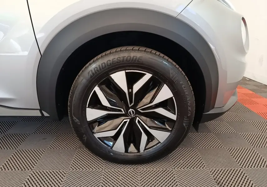 Gros plan sur la roue avant gauche du Nissan Juke gris clair 2023 avec jante alliage noire et argentée au design moderne.