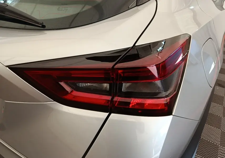 Gros plan sur le feu arrière droit rouge d’un Nissan Juke gris clair 2023, avec partie de la carrosserie visible.