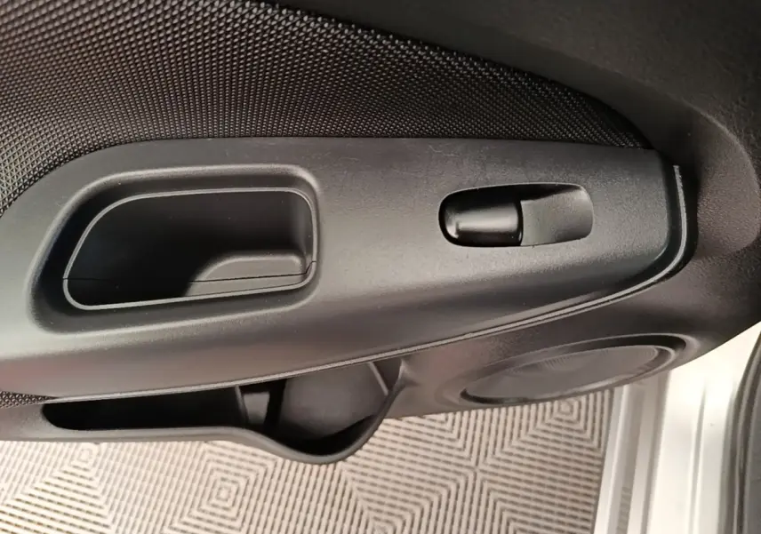 Gros plan sur la poignée intérieure et commande de verrouillage de la porte côté conducteur d'un Nissan Juke gris clair 2023.